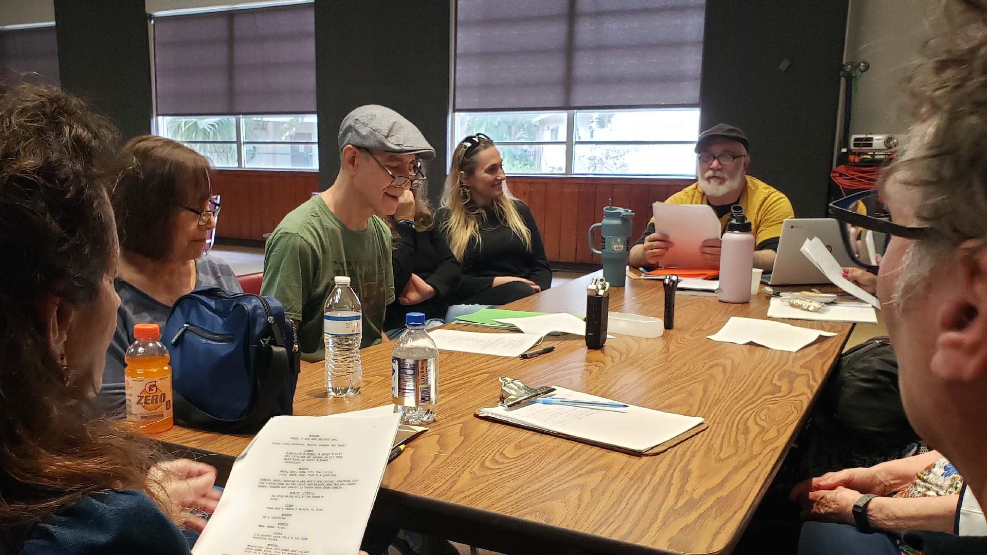Group of actors reading scripts at a table.